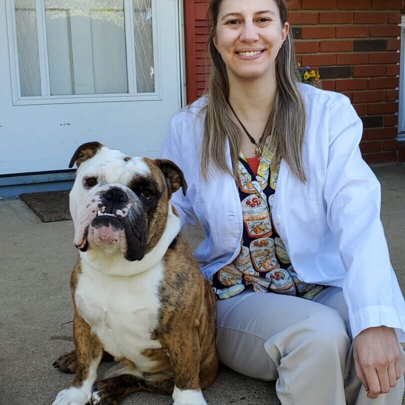 A woman sitting on the ground with her dog.